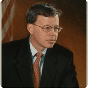 A man in suit and tie sitting at a table.